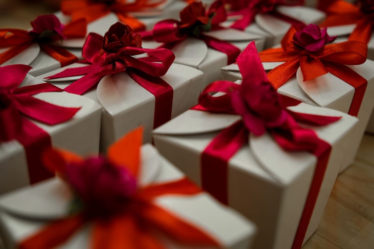 best-selling product-01 Close-up of white gift boxes adorned with vibrant red and orange ribbons, ideal for celebrations.